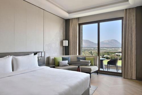 JW Marriott Hotel Bengaluru Prestige Golfshire Resort & Spa في بانغالور: غرفه فندقيه بسرير واريكه