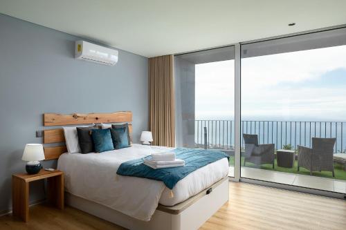 a bedroom with a bed and a large window at King´s Paradise (Heated Pool and Sea View) in Estreito da Calheta