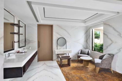 baño con lavabo, espejo y silla en JW Marriott Hotel Bengaluru Prestige Golfshire Resort & Spa en Bangalore