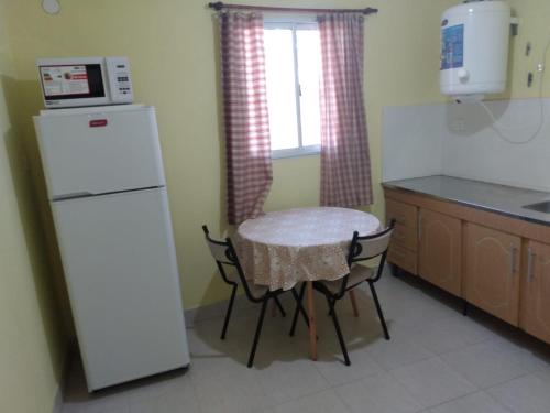 una piccola cucina con tavolo e frigorifero bianco di MARGARITA ALOJAMIENTO TEMPORARIO a San Fernando del Valle de Catamarca