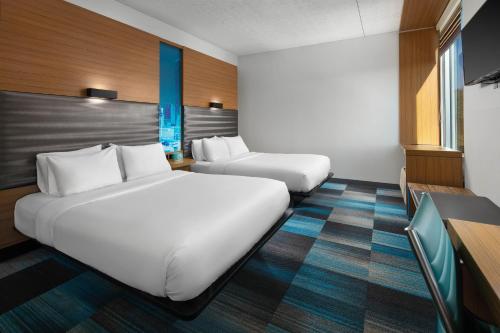 a hotel room with two beds and a tv at Aloft BWI Baltimore Washington International Airport in Linthicum Heights