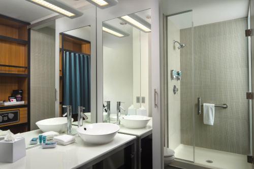a bathroom with two sinks and a shower at Aloft BWI Baltimore Washington International Airport in Linthicum Heights
