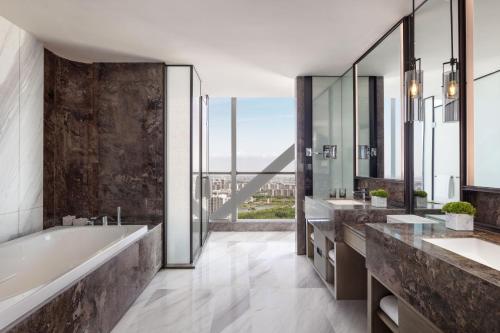 ein Badezimmer mit zwei Waschbecken, einer Badewanne und einem großen Fenster in der Unterkunft JW Marriott Hotel Yinchuan in Yinchuan