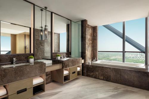 a bathroom with two sinks and a tub and windows at JW Marriott Hotel Yinchuan in Yinchuan