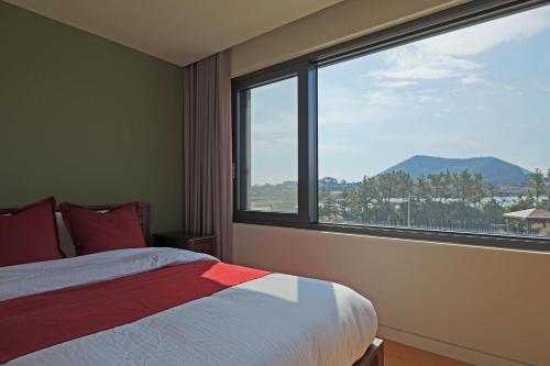 a bedroom with a bed and a large window at Jimi Stay in Jeju