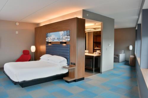 a bedroom with a bed and a desk with a red chair at Aloft Raleigh in Raleigh