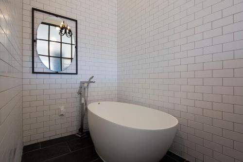 a white bathroom with a tub and a mirror at Jimi Stay in Jeju