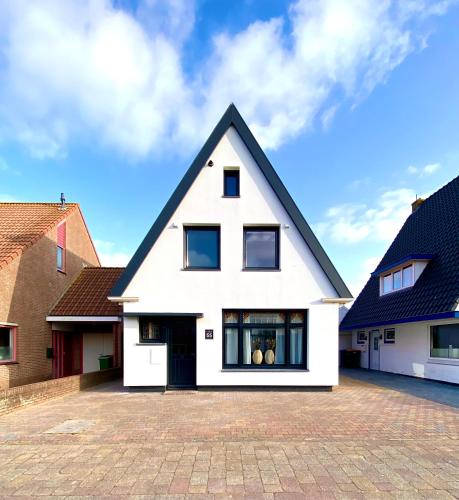a white house with a black roof at The island life beach house 1 in De Koog