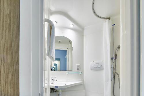 La salle de bains blanche est pourvue d'un lavabo et d'un miroir. dans l'établissement Goldsmid House, Victoria, à Londres