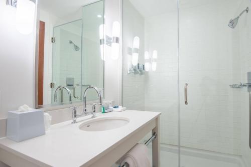 uma casa de banho branca com um lavatório e um chuveiro em Four Points by Sheraton Saskatoon em Saskatoon
