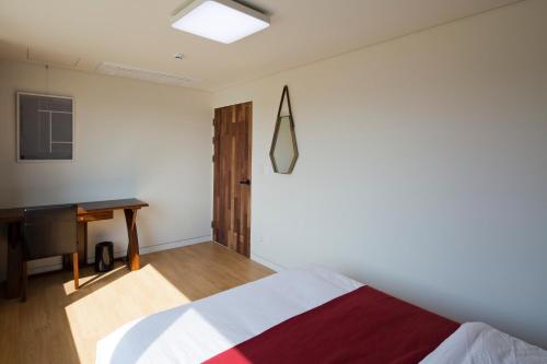 a bedroom with a bed and a desk in it at Jimi Stay in Jeju