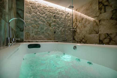 a bathroom with a tub filled with blue water at Black Rocks Luxury Seafront Beach Suite in Agios Gordios