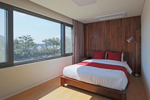 a bedroom with a bed with red pillows and a large window at Jimi Stay in Jeju