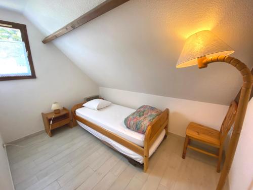 Habitación pequeña con cama, lámpara y silla en Le Clos des Dunes, maison à Erdeven, en Erdeven