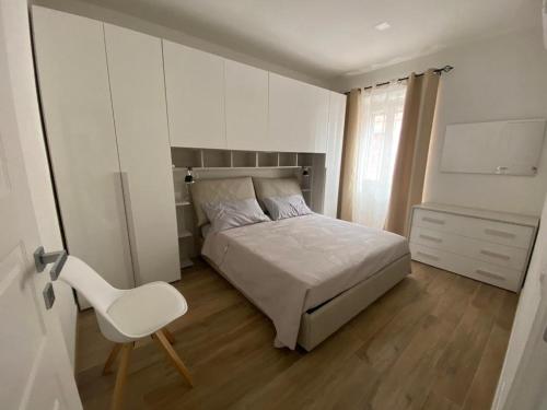 een slaapkamer met een bed en een witte stoel bij Le Pavoncelle in Valledoria