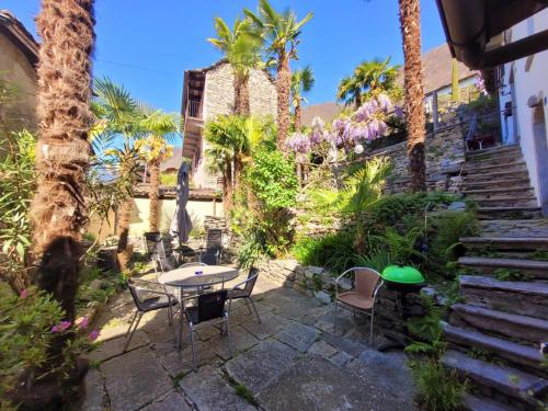 a patio with a table and chairs and palm trees at Casa Grillino in Brione sopra Minusio