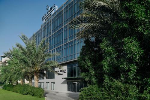 a building with a palm tree in front of it at Delta Hotels by Marriott Dubai Investment Park in Dubai
