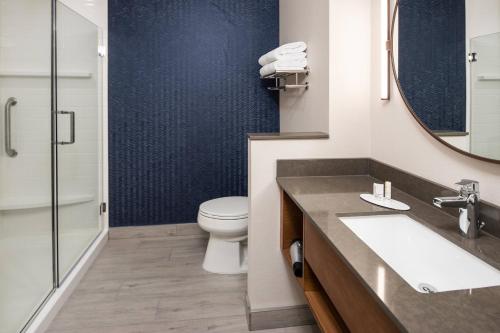 a bathroom with a toilet and a sink and a mirror at Fairfield by Marriott Inn & Suites Anaheim Los Alamitos in Los Alamitos