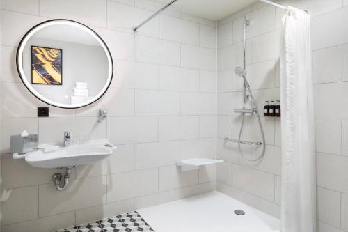 Baño blanco con lavabo y espejo en Residence Inn by Marriott Brussels Airport, en Diegem