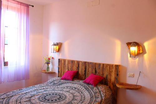 Un dormitorio con una cama con almohadas rosas y una ventana en La terrazza sugli aranci, en Rio Marina
