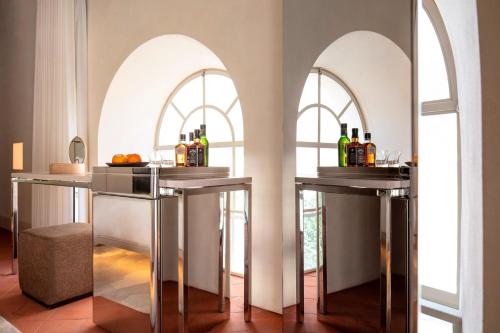 a bar with two arched windows and bottles of wine at The Jaffa - Fattal Limited Edition in Tel Aviv
