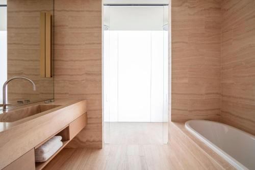 a bathroom with a tub and a sink and a shower at The Jaffa - Fattal Limited Edition in Tel Aviv