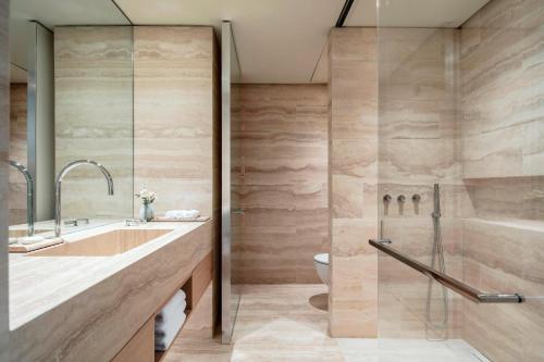 a bathroom with a shower and a sink and a toilet at The Jaffa - Fattal Limited Edition in Tel Aviv
