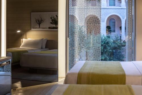 a hotel room with two beds and a window at The Jaffa - Fattal Limited Edition in Tel Aviv