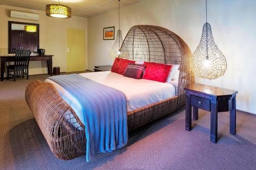 a bedroom with a large bed with a wooden headboard at Protea Hotel by Marriott Zambezi River Lodge in Katima Mulilo