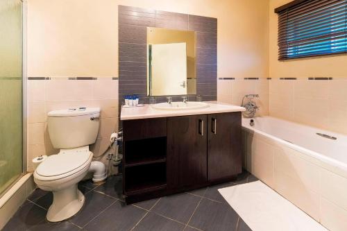 a bathroom with a toilet and a sink and a tub at Protea Hotel by Marriott Zambezi River Lodge in Katima Mulilo
