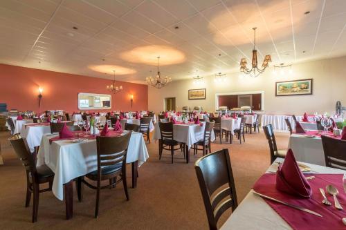 a dining room with white tables and chairs with red napkins at Protea Hotel by Marriott Zambezi River Lodge in Katima Mulilo