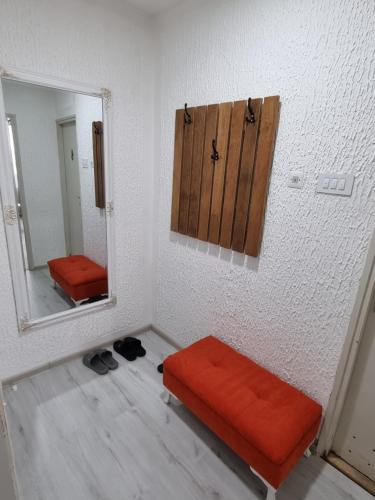 una habitación con un reposapiés naranja y un espejo en CENTRAL, en Kruševac
