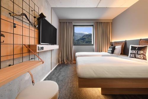 a hotel room with two beds and a tv at Moxy Sion in Sion