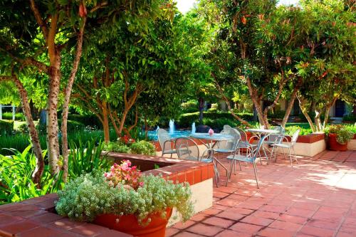 a patio with tables and chairs and plants and trees at Four Points by Sheraton Pleasanton in Pleasanton