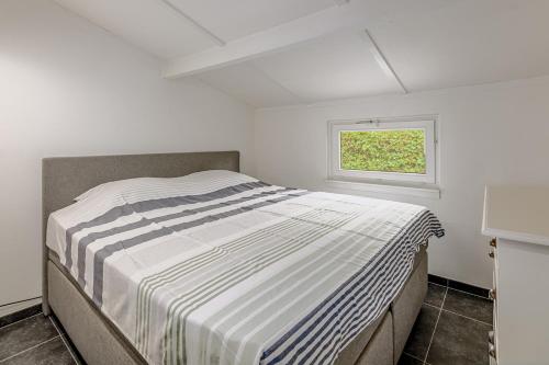 een bed in een witte kamer met een raam bij De Zeevijver Oostduinkerke in Oostduinkerke