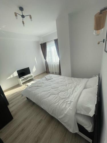 una camera bianca con letto e televisore di West View by DAT Apartments a Cluj-Napoca