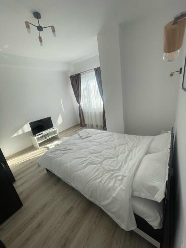 a white bedroom with a bed and a television at West View by DAT Apartments in Cluj-Napoca