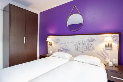 a bedroom with a large white bed and a purple wall at Les Pins Blancs en Provence in Le Muy