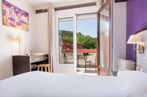 a hotel room with a bed and a view of a balcony at Les Pins Blancs en Provence in Le Muy