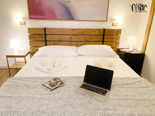 a laptop computer sitting on a bed with a book at Hotel Nizza Creative Hotel in Rimini