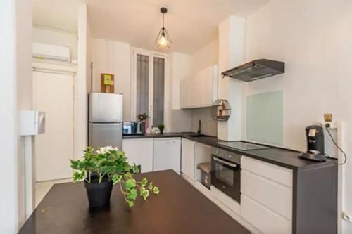 une cuisine avec des armoires blanches et un comptoir noir dans l'établissement T2 Appartement lumineux à la Joliette, à Marseille