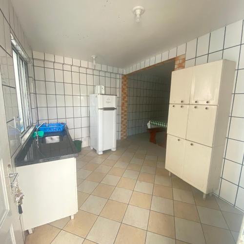 a kitchen with a refrigerator and a tiled floor at GH Barra da Lagoa in Florianópolis