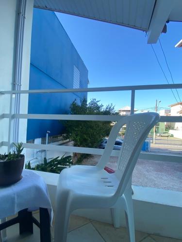 a white chair sitting in front of a window at Barra da Lagoa Guest House in Florianópolis