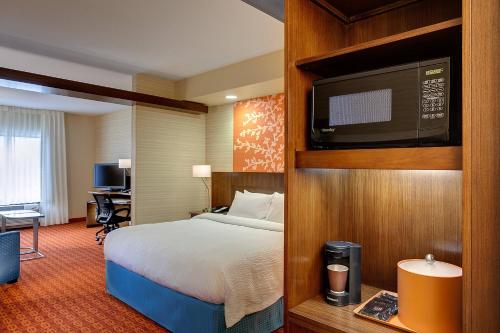 a hotel room with a bed and a flat screen tv at Fairfield Inn & Suites Lincoln Crete in Crete