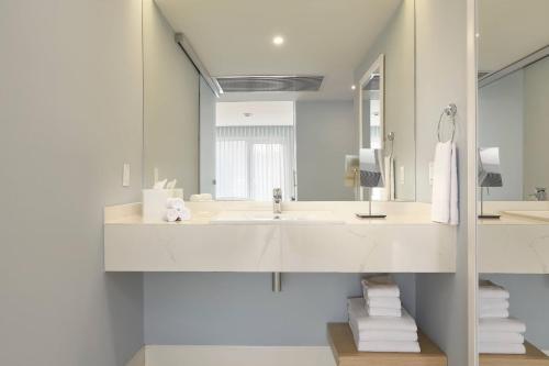 a white bathroom with a sink and a mirror at Courtyard by Marriott Aruba Resort in Palm-Eagle Beach