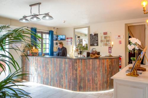 a woman standing at a bar in a restaurant at Les Pins Blancs en Provence in Le Muy