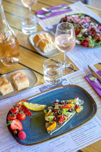 a table with a plate of food and glasses of wine at Les Pins Blancs en Provence in Le Muy