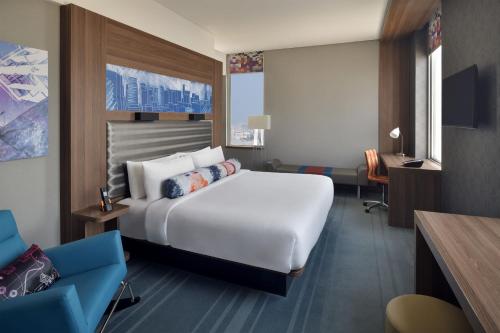 um quarto de hotel com uma cama branca e um sofá azul em Aloft Dhahran Hotel em Al Khobar