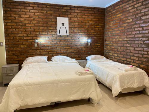2 camas en un dormitorio con una pared de ladrillo en Posada Patagonia Bed & Breakfast en San Juan