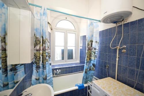 baño de azulejos azules con aseo y ventana en City View Apartment, en Kotor